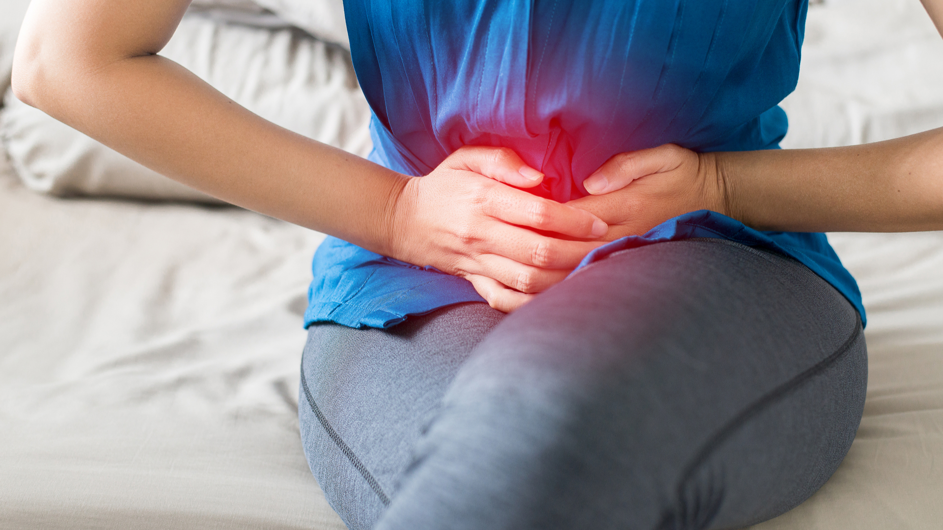 Woman with P.O.P. holding her stomach in pain with red glowing light over her hands